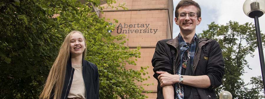 The image shows Jamie Williams and Jordan Han standing outside the Abertay library