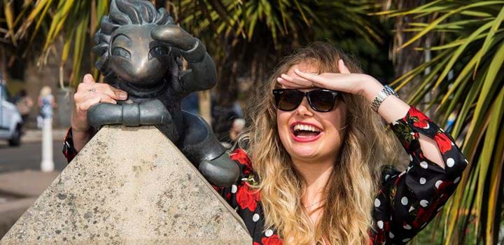 Student smiling in sunglasses with lemming statue