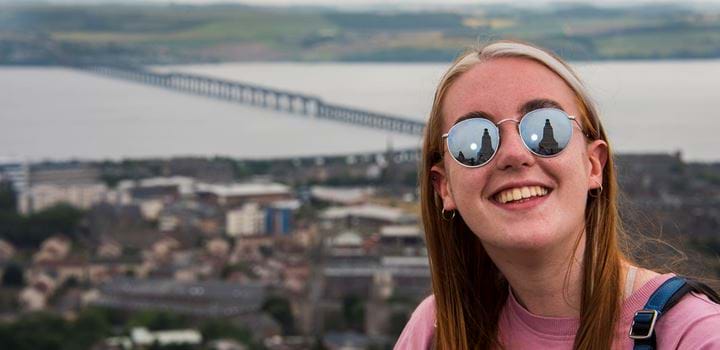Student in sunglasses stood on Dundee Law with the river behind her