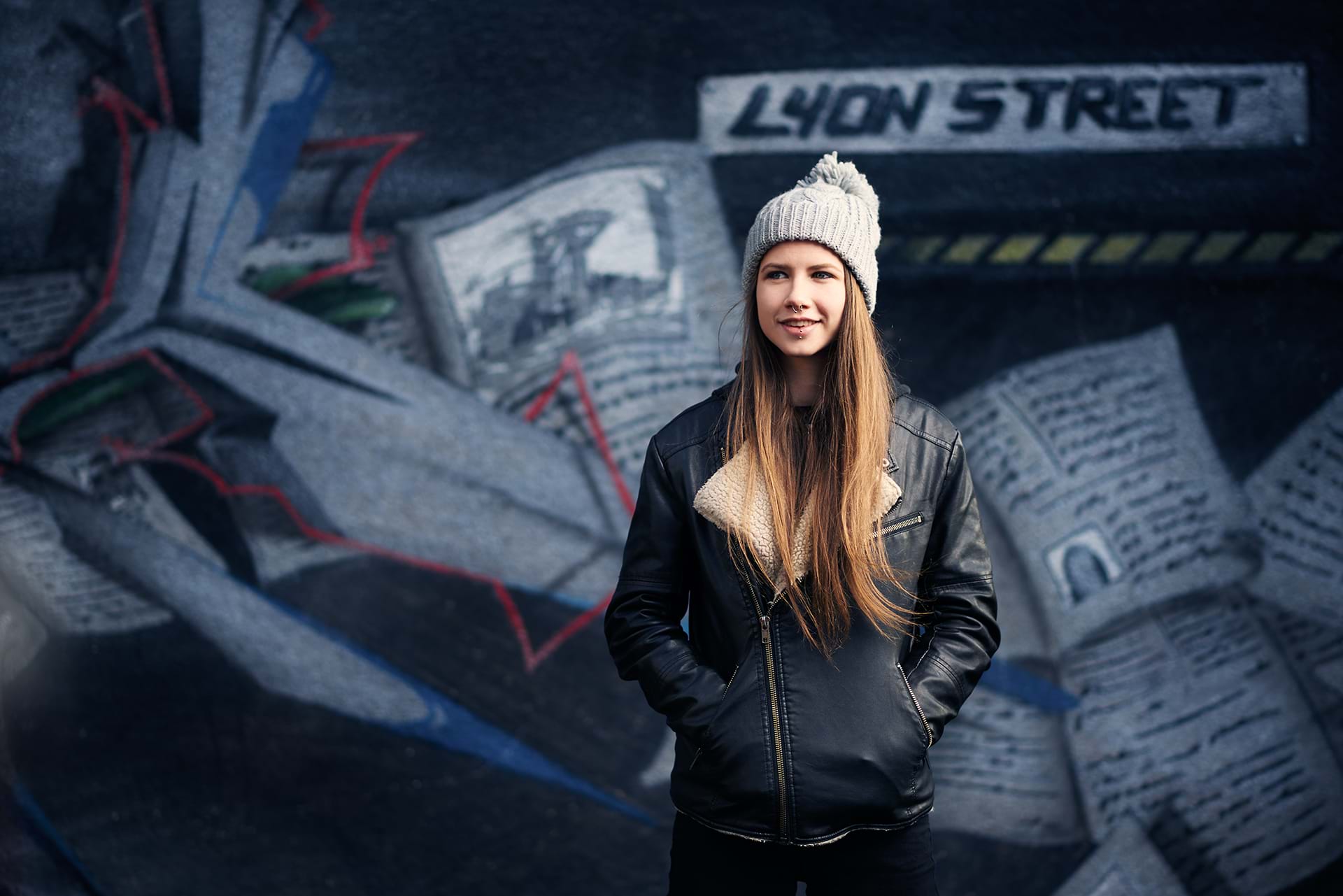 A female student standing outside a graffiti mural of Lyon Street