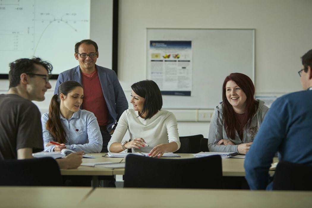 Classroom environment - lecturer standing - students sitting working