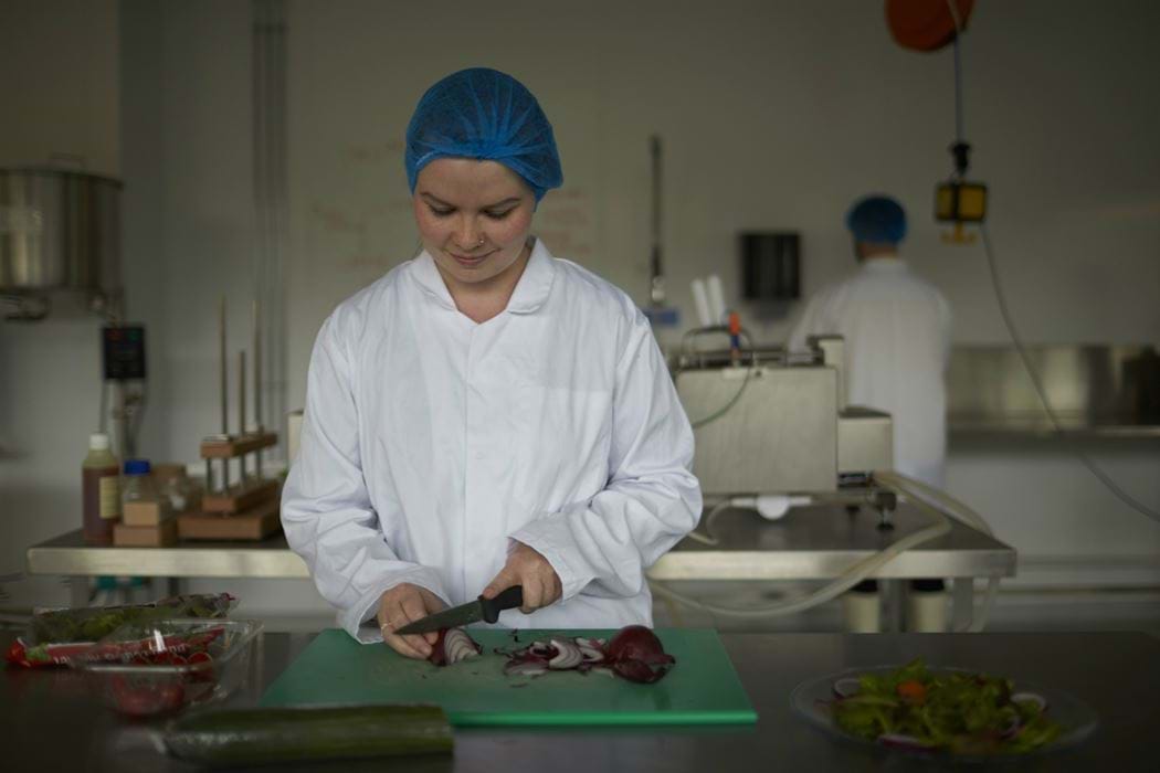 Female using knife and chopping board to prepare food