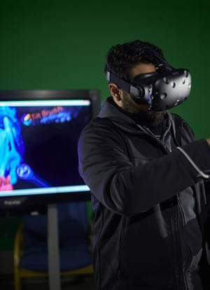 Male wearing Virtual Reality head - female watching in background 