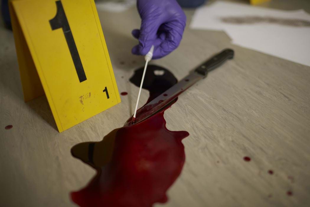 A hand can be seen using a cotton swab to take a sample from a blood stained knife