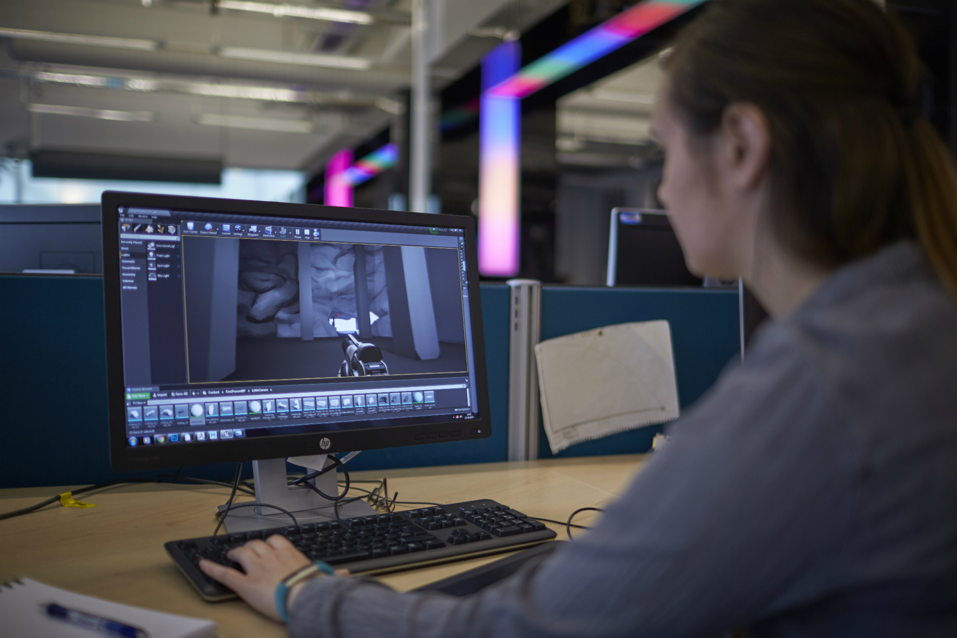 A female student sitting at a desk and working at a computer on a video game