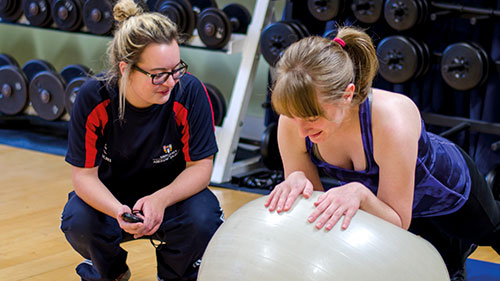 Student coaching female in gym