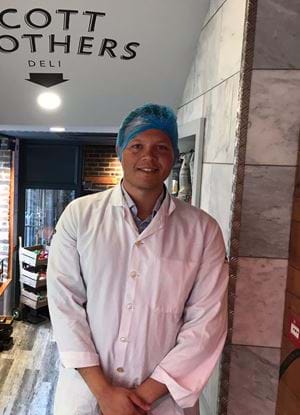 A picture of Samuel Ceolin wearing a hairnet and apron at Scott Brothers Butcher