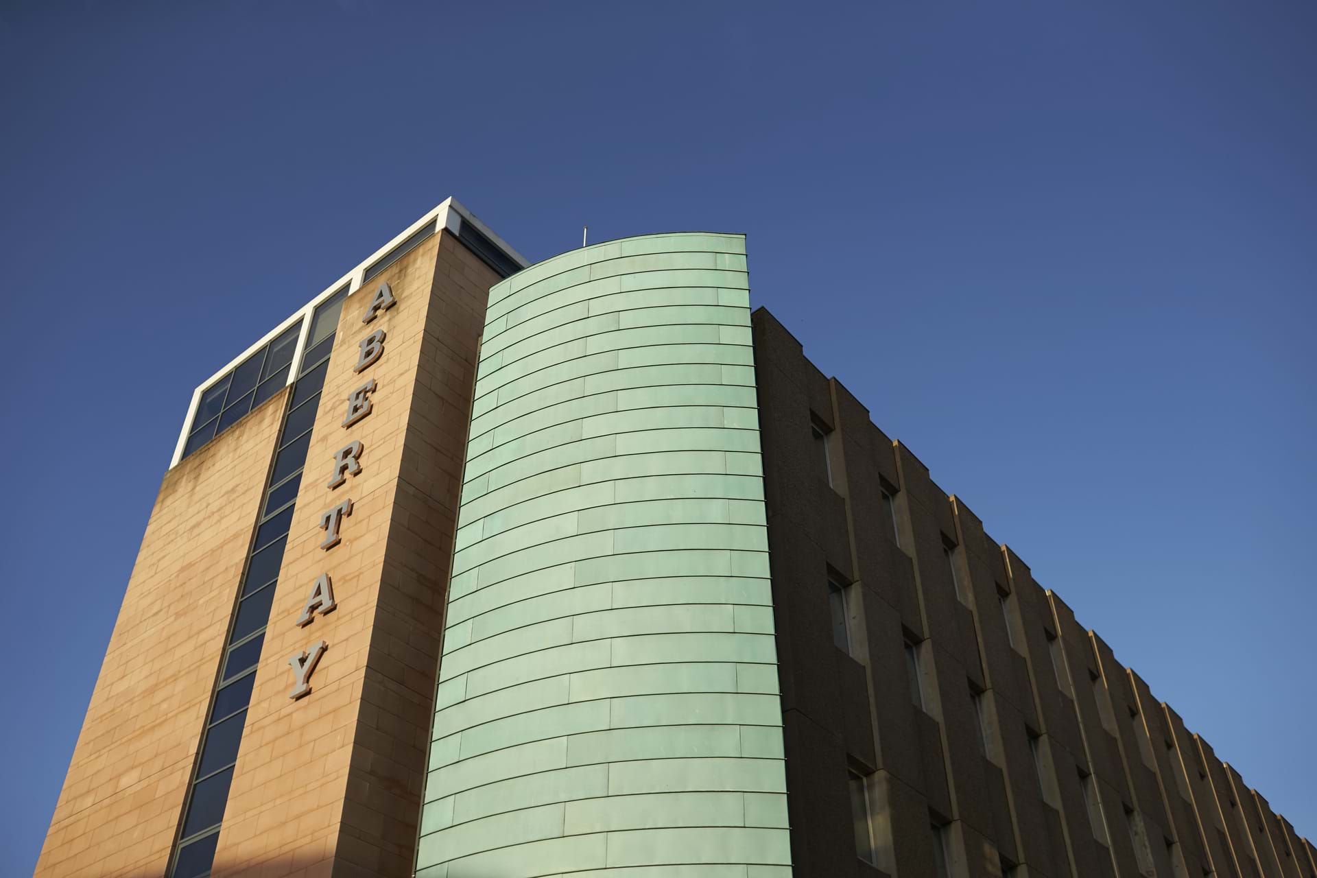 The building shows the Abertay building with a blue sky behind.