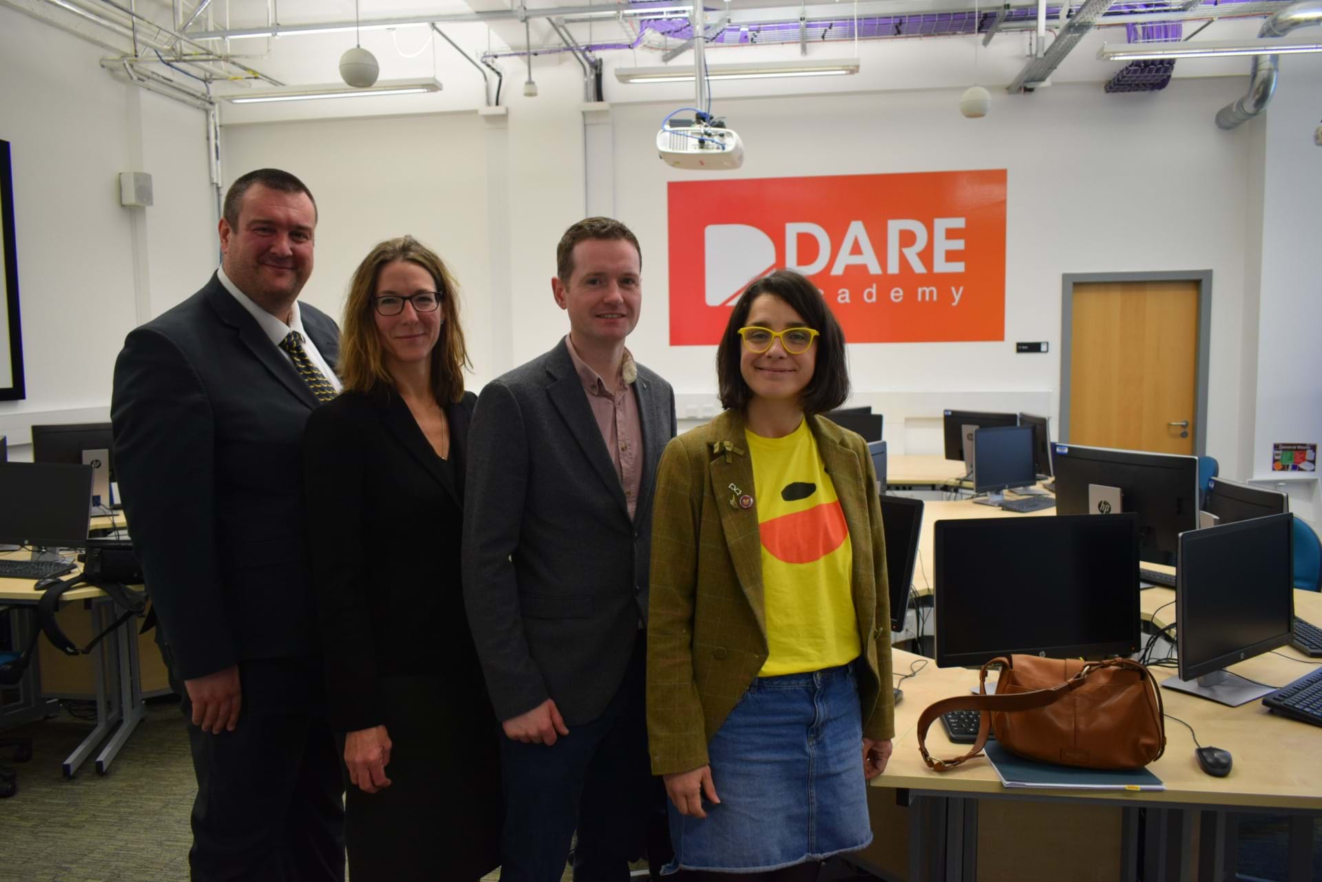 Alisdair McNaughton, Kate Wyatt, Chris Forde and lecturer Lynne Love in front of a Dare Academy logo