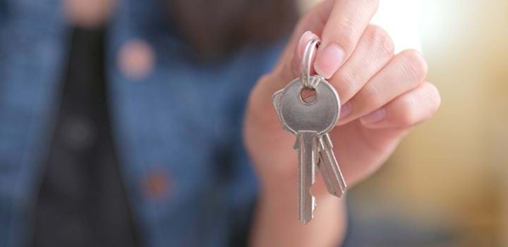 A photo of a hand holding a pair of keys. The background of the photo is blurred to emphasise the keys.