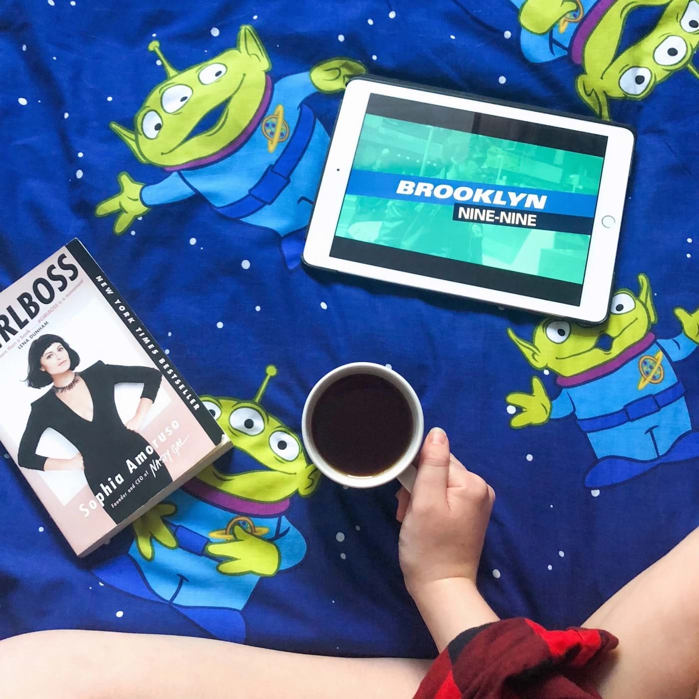 A duvet featuring the aliens from Toy Story, with a hand holding a cup of tea
