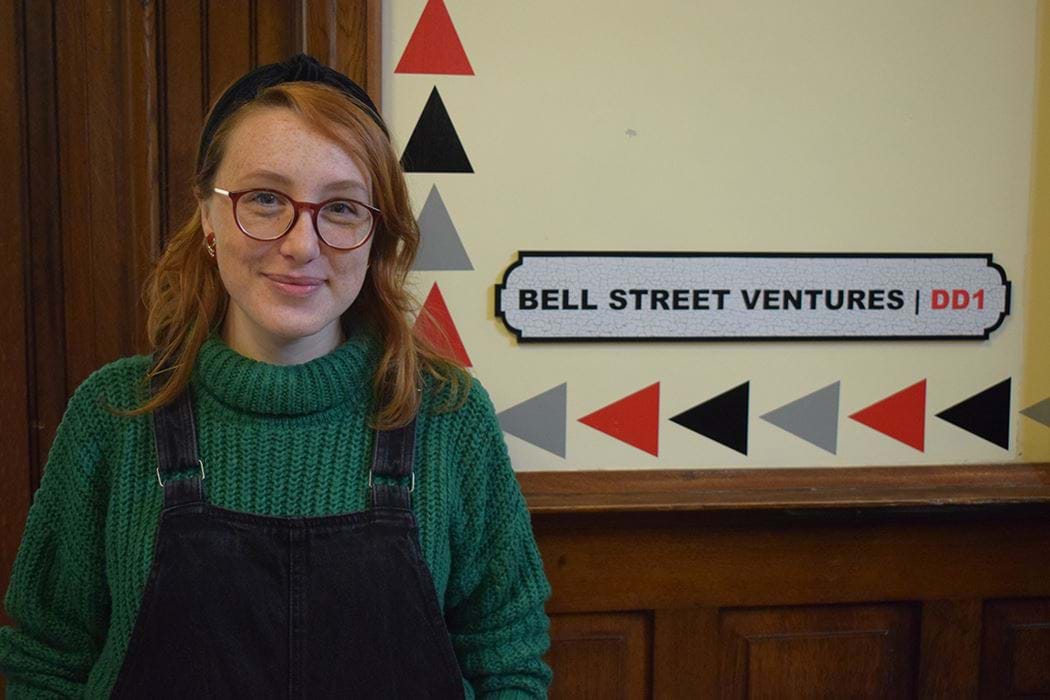 A picture of Stephanie Crowe standing in front of a sign with the words "Bell Street Ventures" on it.