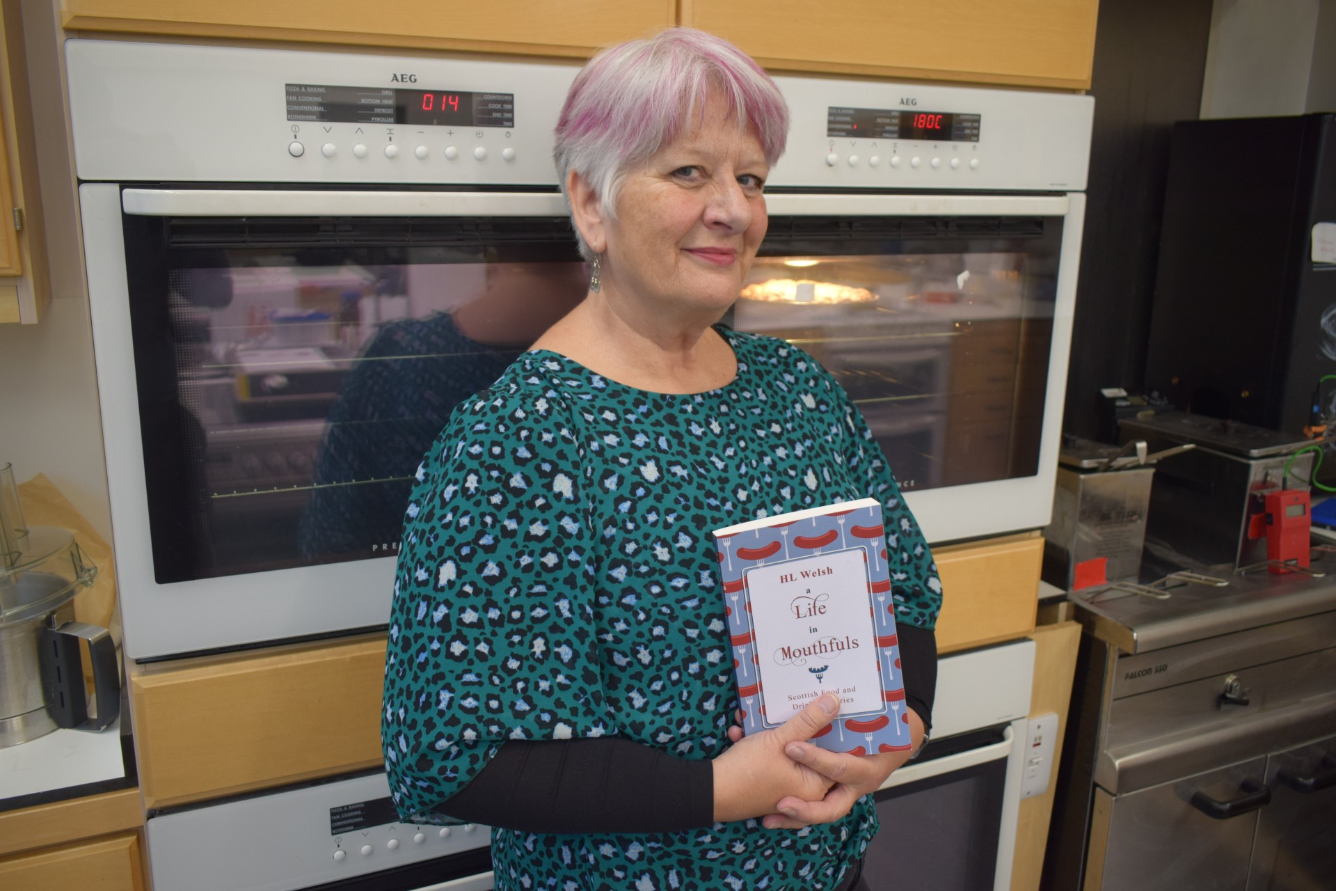 A photo of Helen Welsh holding her new book