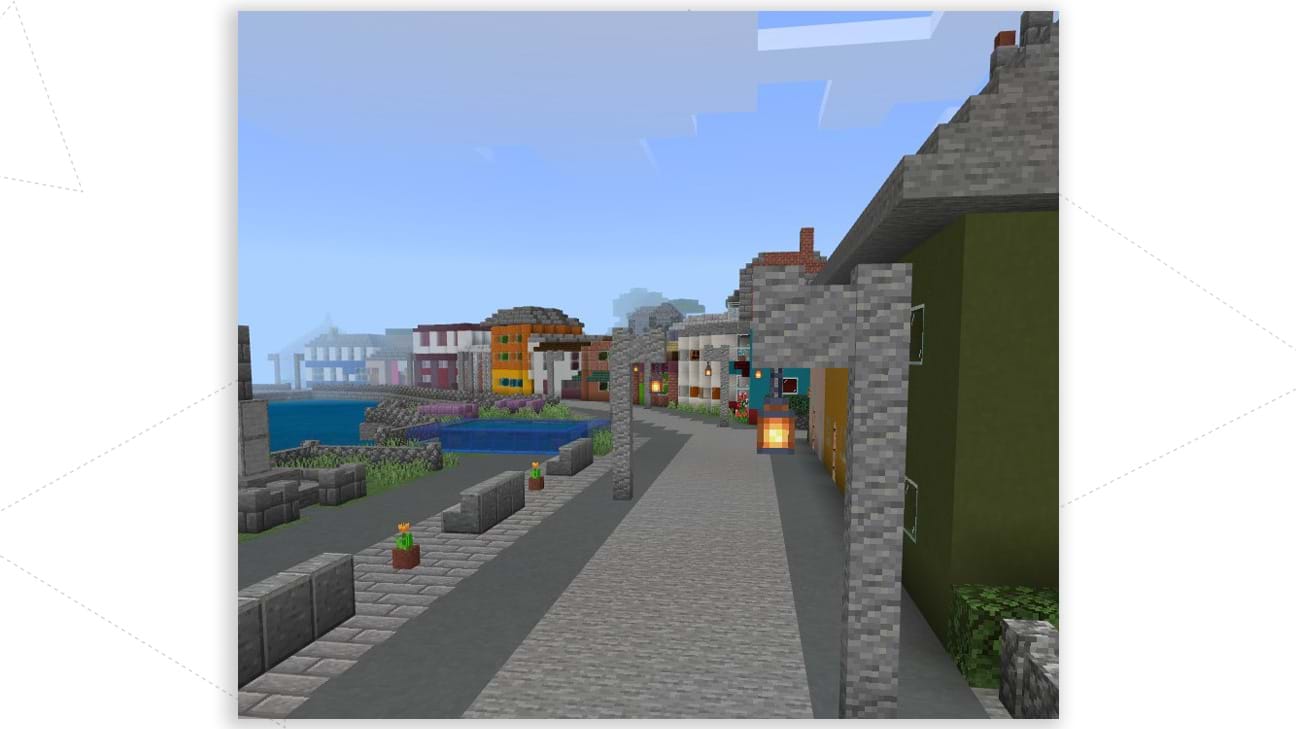 The image shows the portside street of the Isle of Cumbrae in Minecraft. Water is to the left of the image with buildings on the right and the harbour road and wall cuts through the middle. 