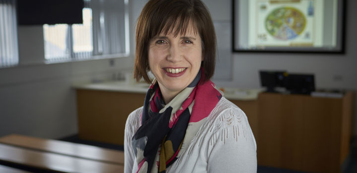 A woman with short brown hair standing in a classroom. 