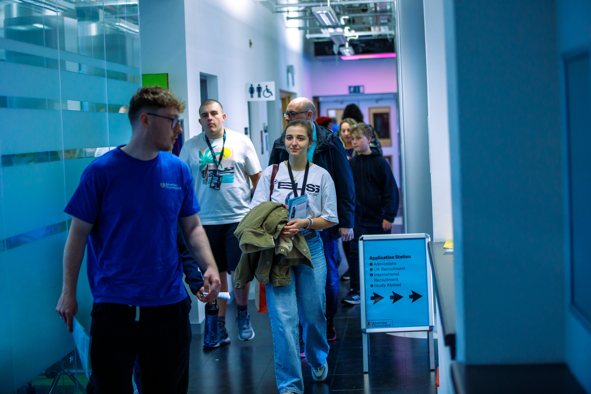 Student event helper in blue t-shirt giving a campus tour to potential applicants